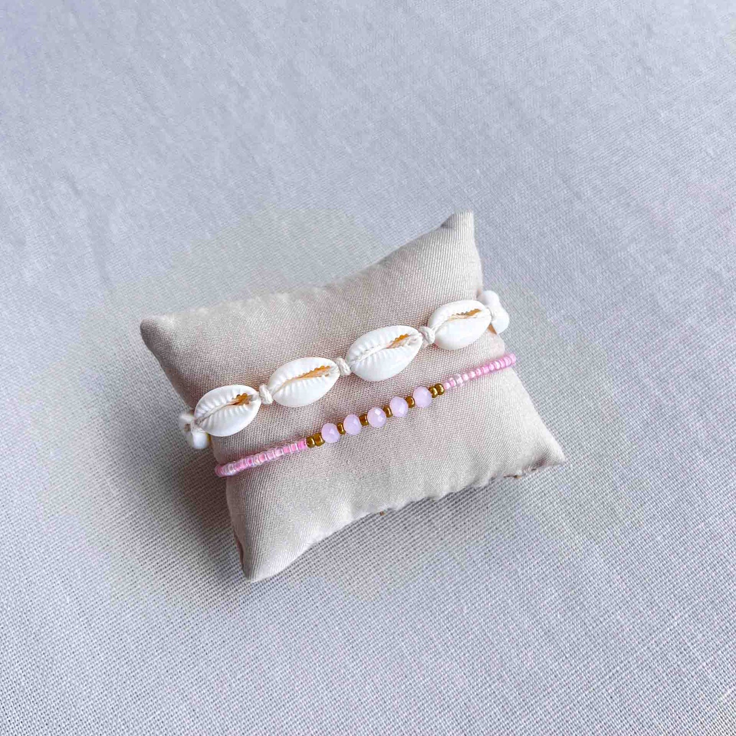 Roze gekleurd armbandje met kralen om een kussentje