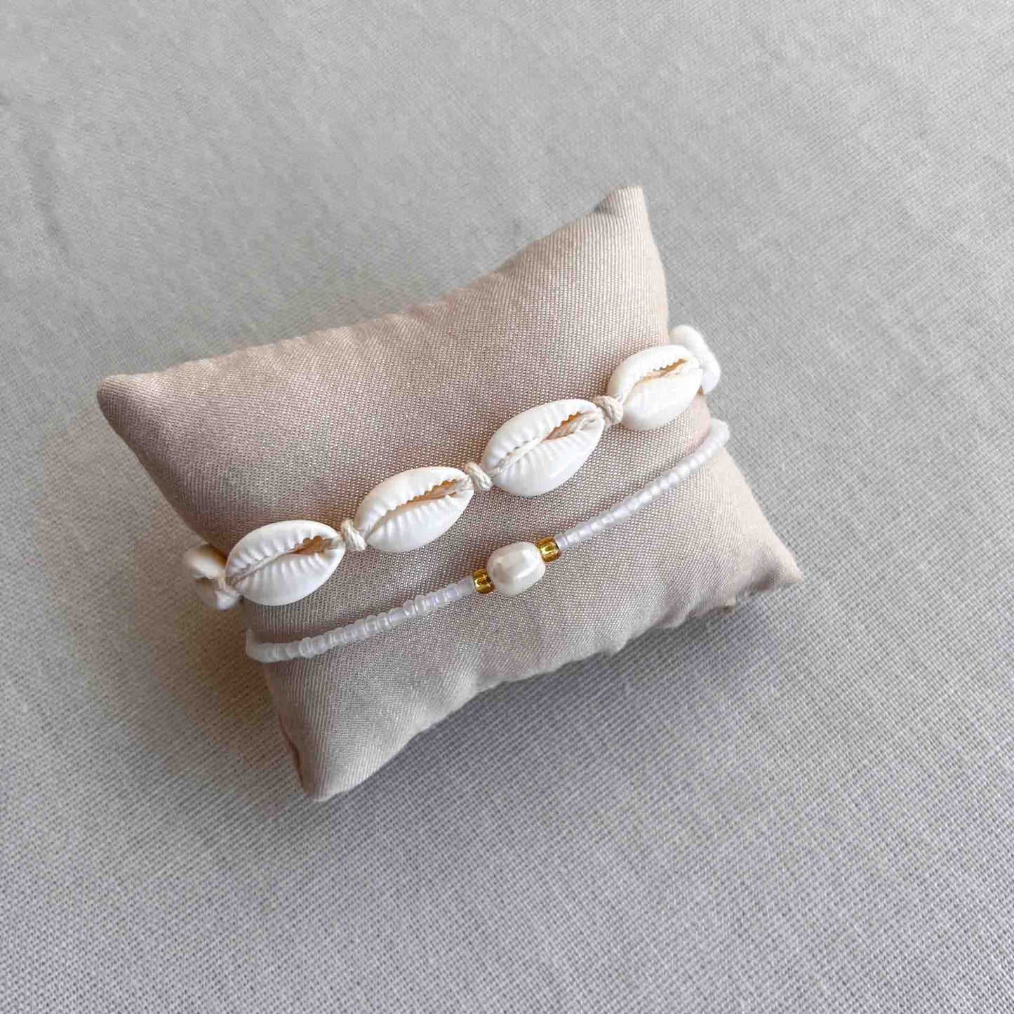 Armbandje met kauri schelpjes om een kussentje