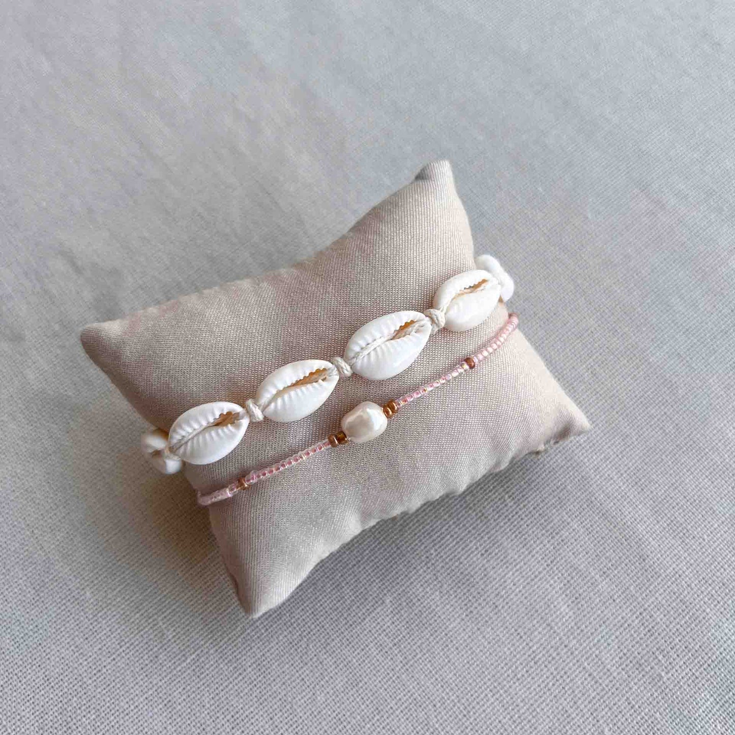 Armbandje met kauri schelpjes om een kussentje