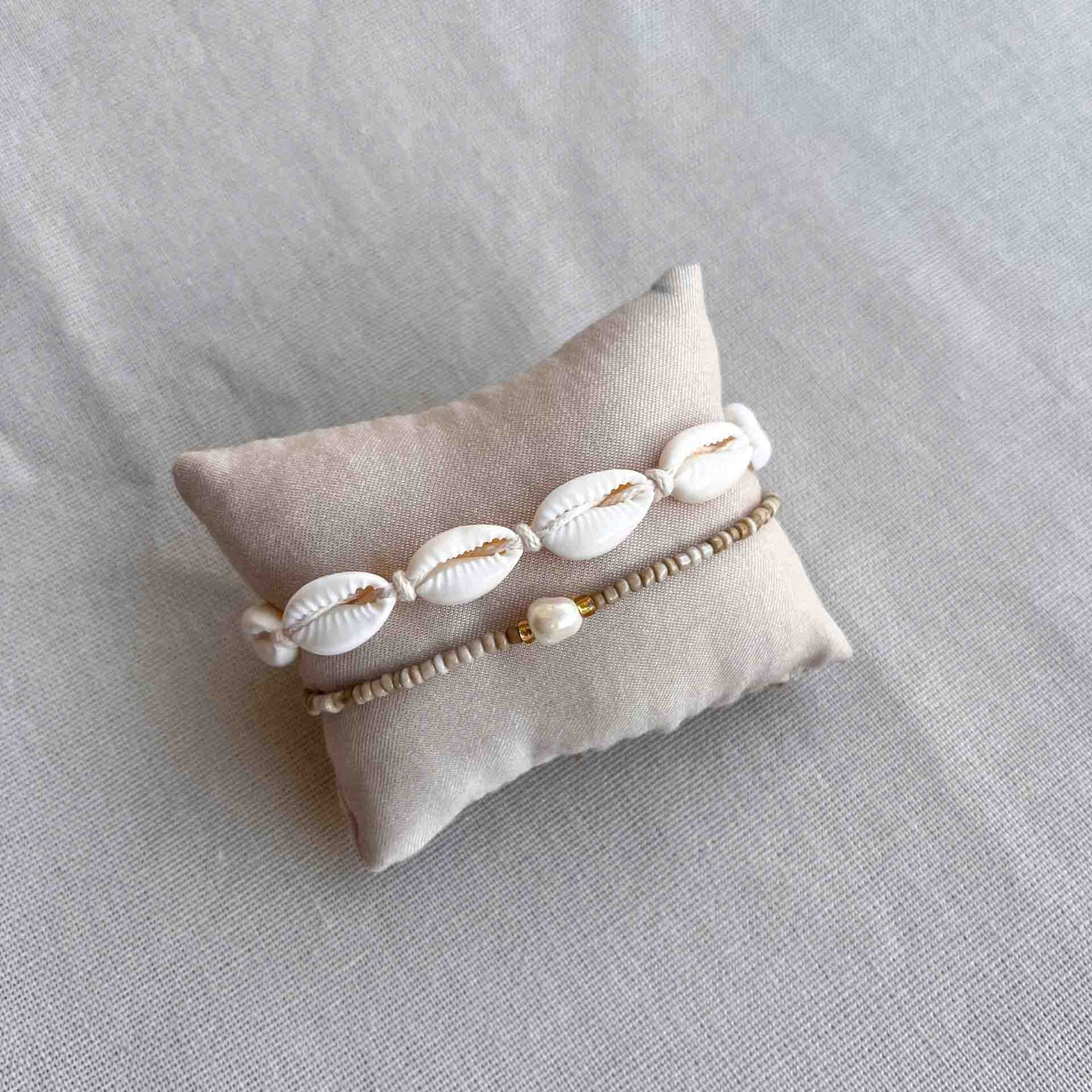 Armbandje met kauri schelpjes om een kussentje