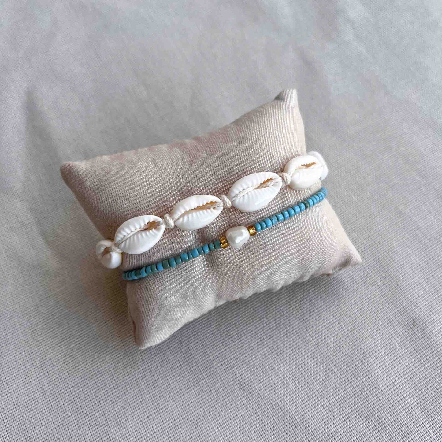 Armbandje met kauri schelpjes om een kussentje