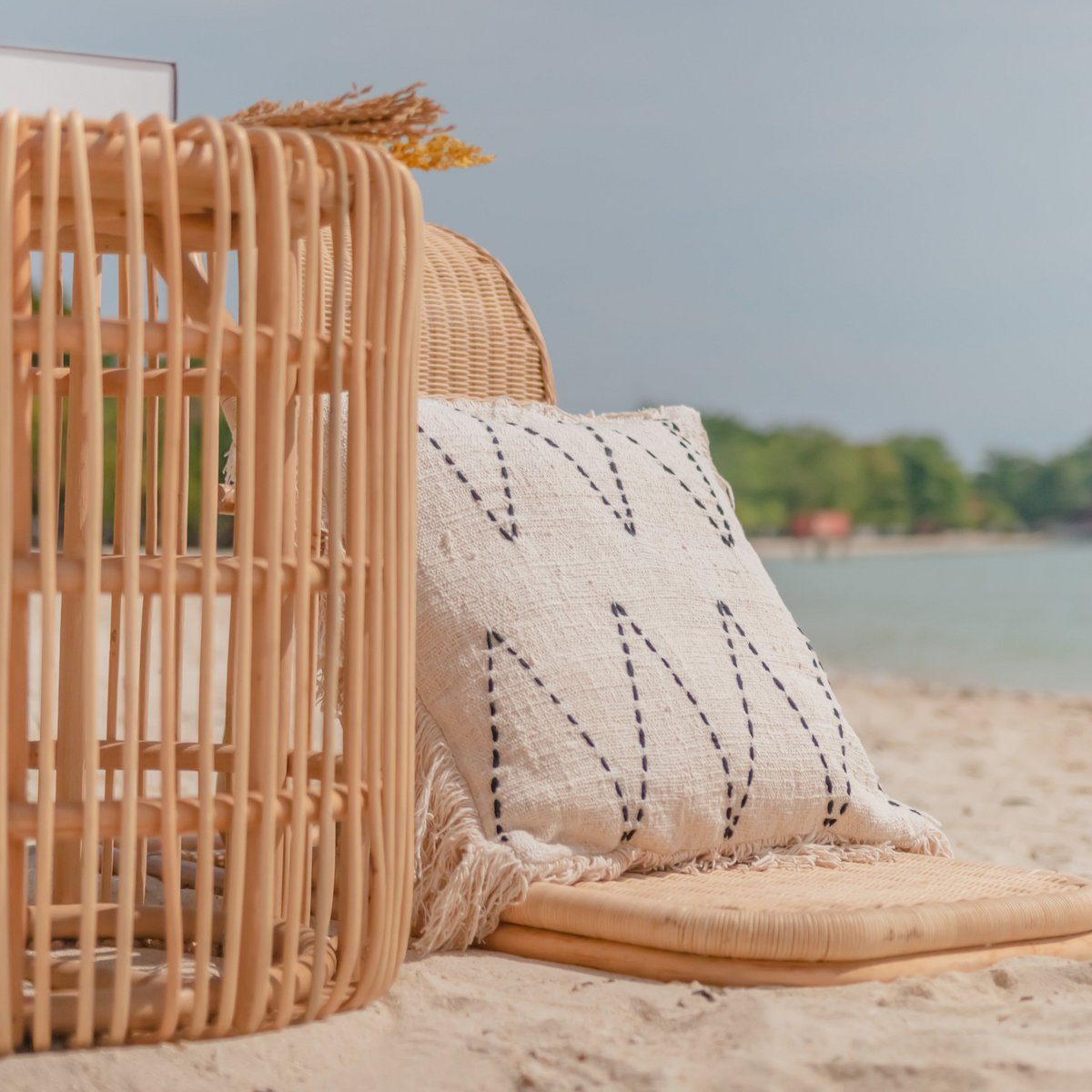 Bijzettafel van rotan op het strand met een kussen ernaast