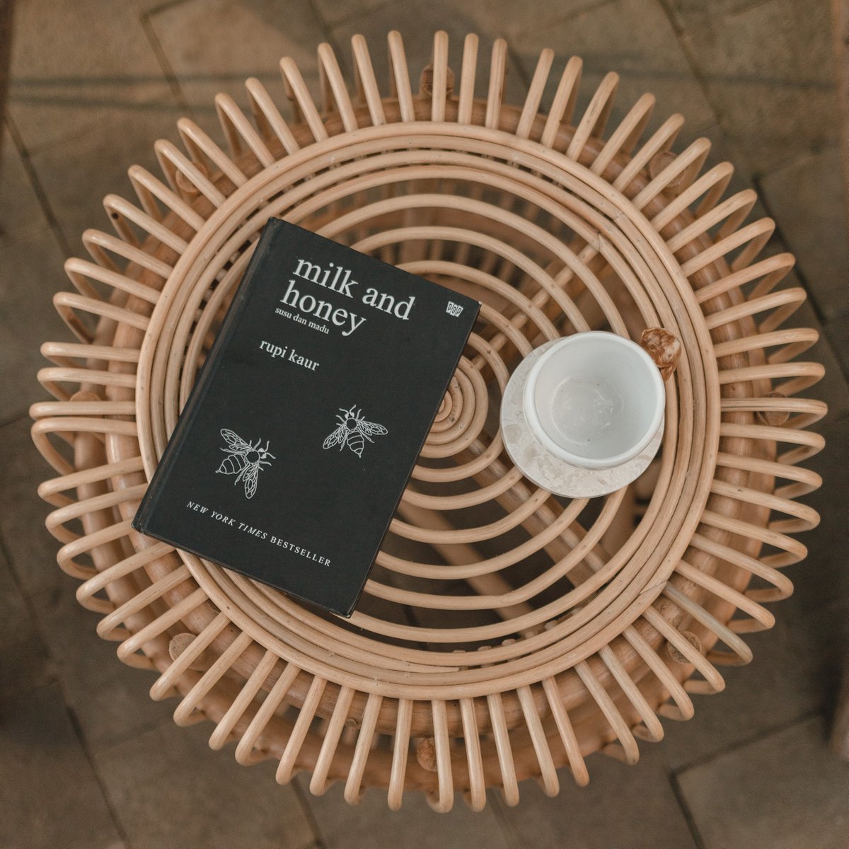 Bijzettafel van rotan met een boek en kopje erop van boven gezien