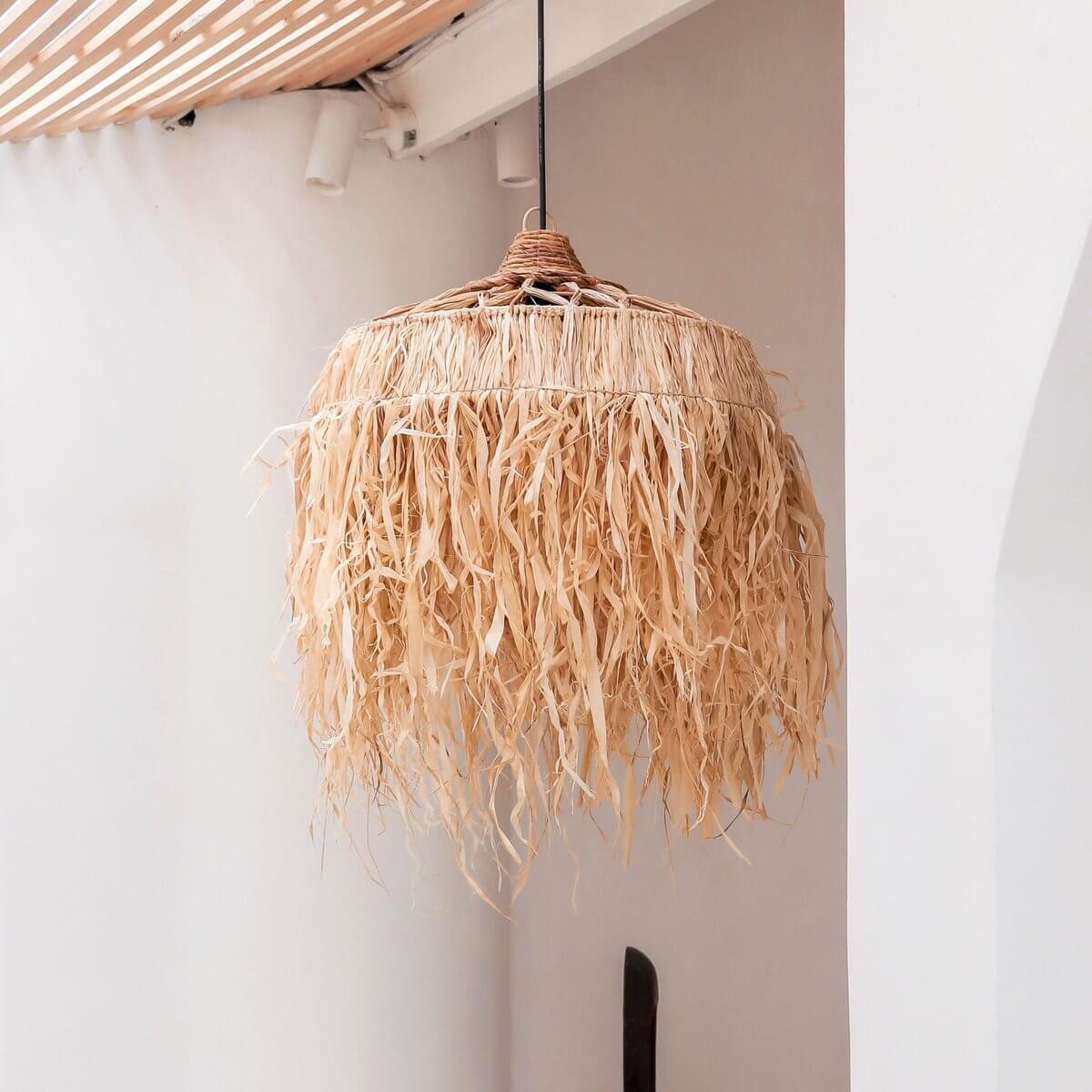 Lampenkap van raffia hangend voor een witte muur