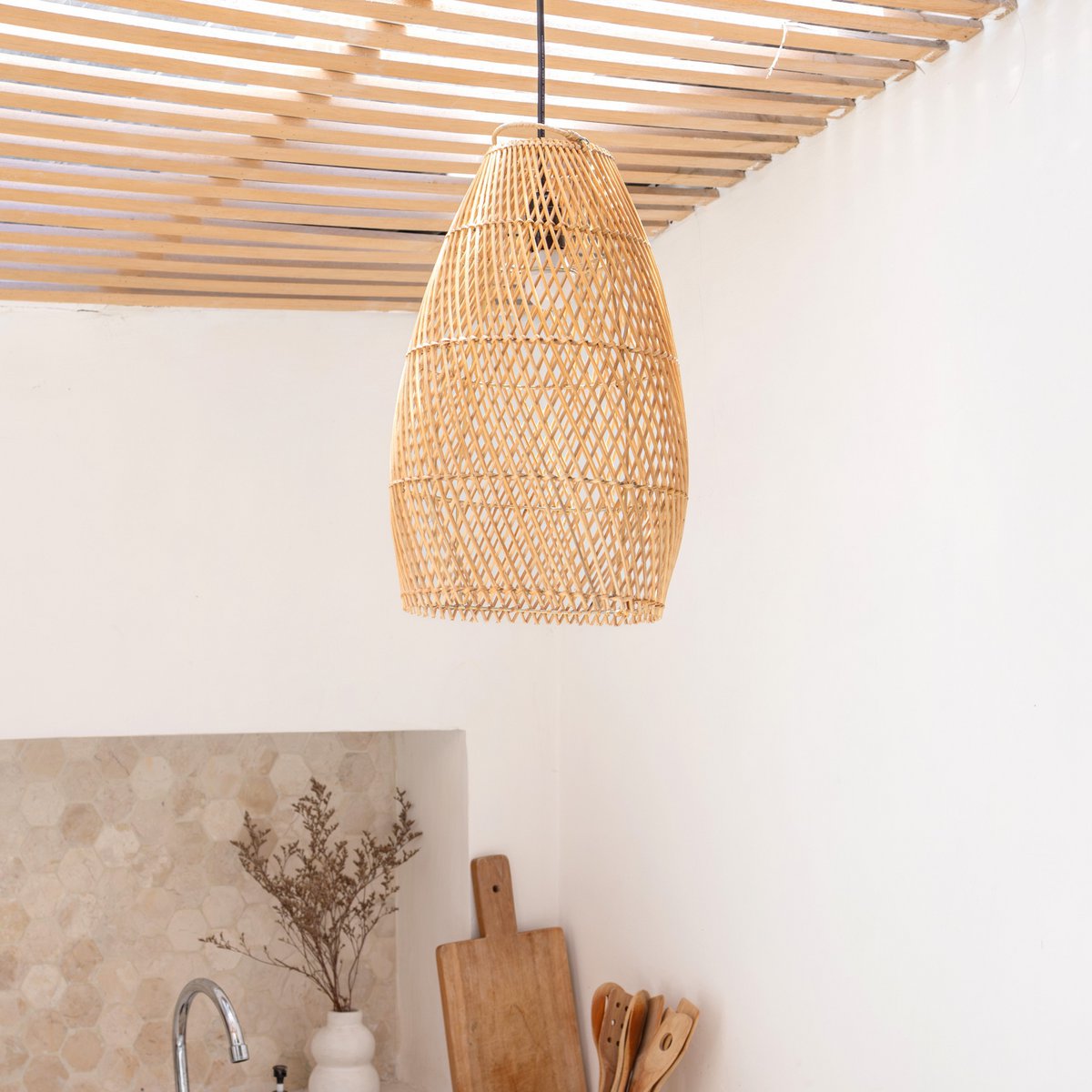 Lampenkap van rotan hangend boven een keuken met witte muren