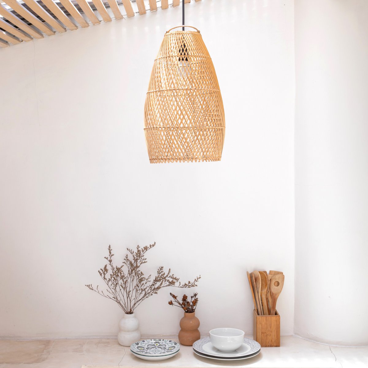 Hanglamp van rotan hangend voor een witte muur