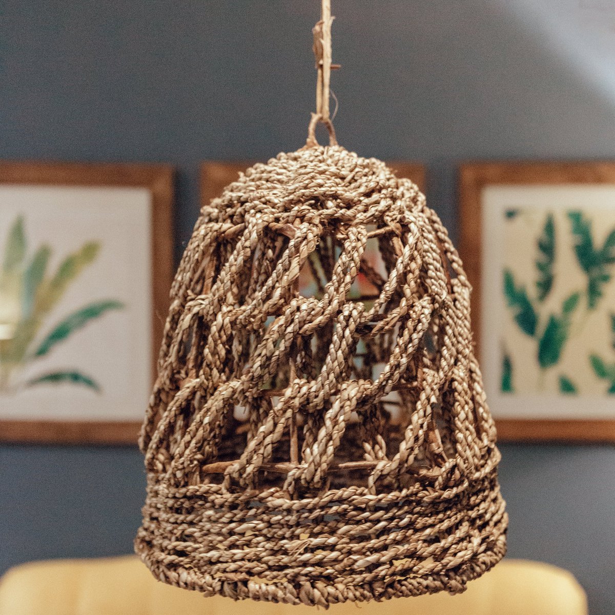 Hanglamp van zeegras voor een blauwe muur