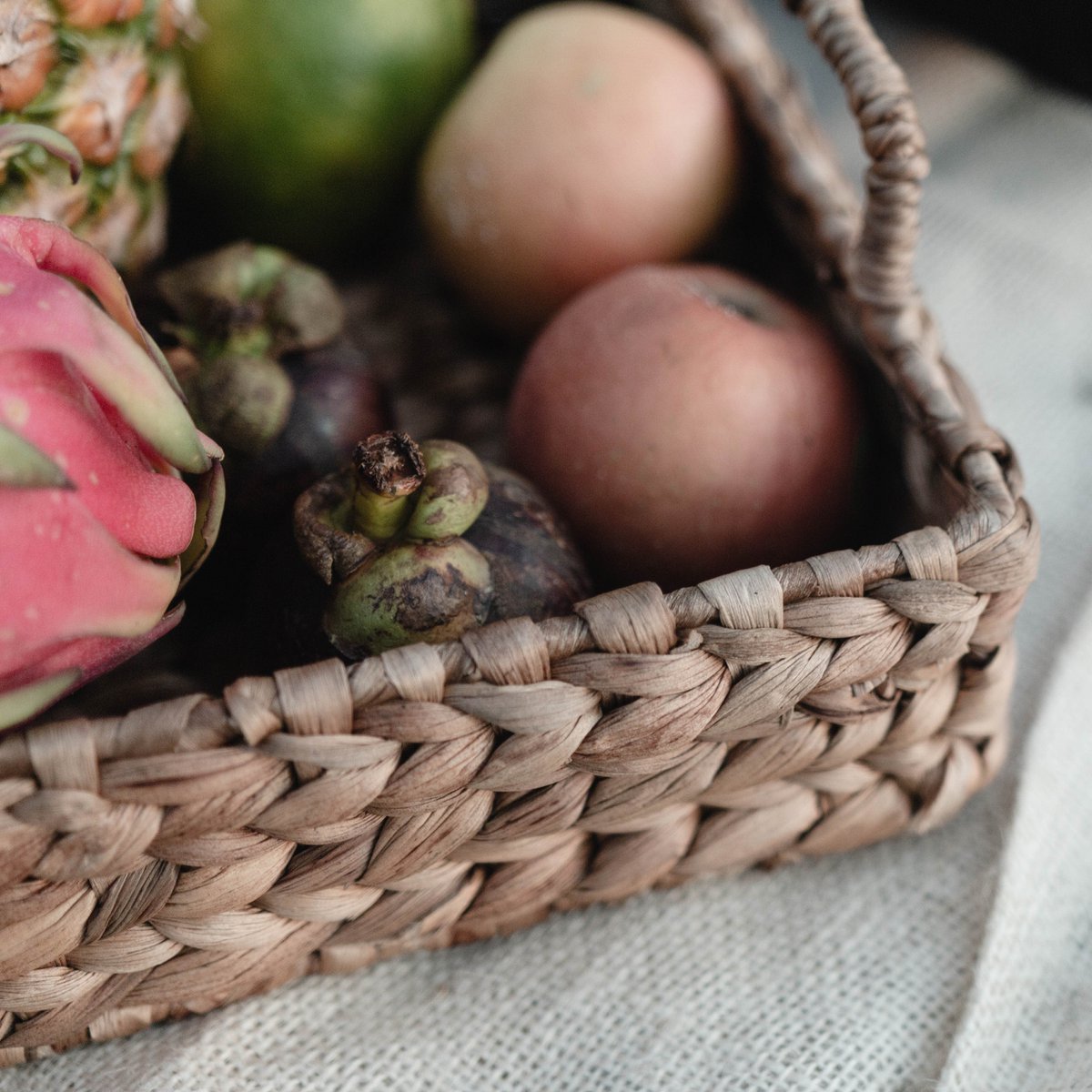 Een dienblad met handvat van waterhyacint van dichtbij gezien met daarin een aantal stukken fruit