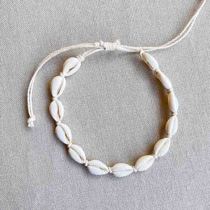Enkelbandje met kauri schelpjes op een zijden doek