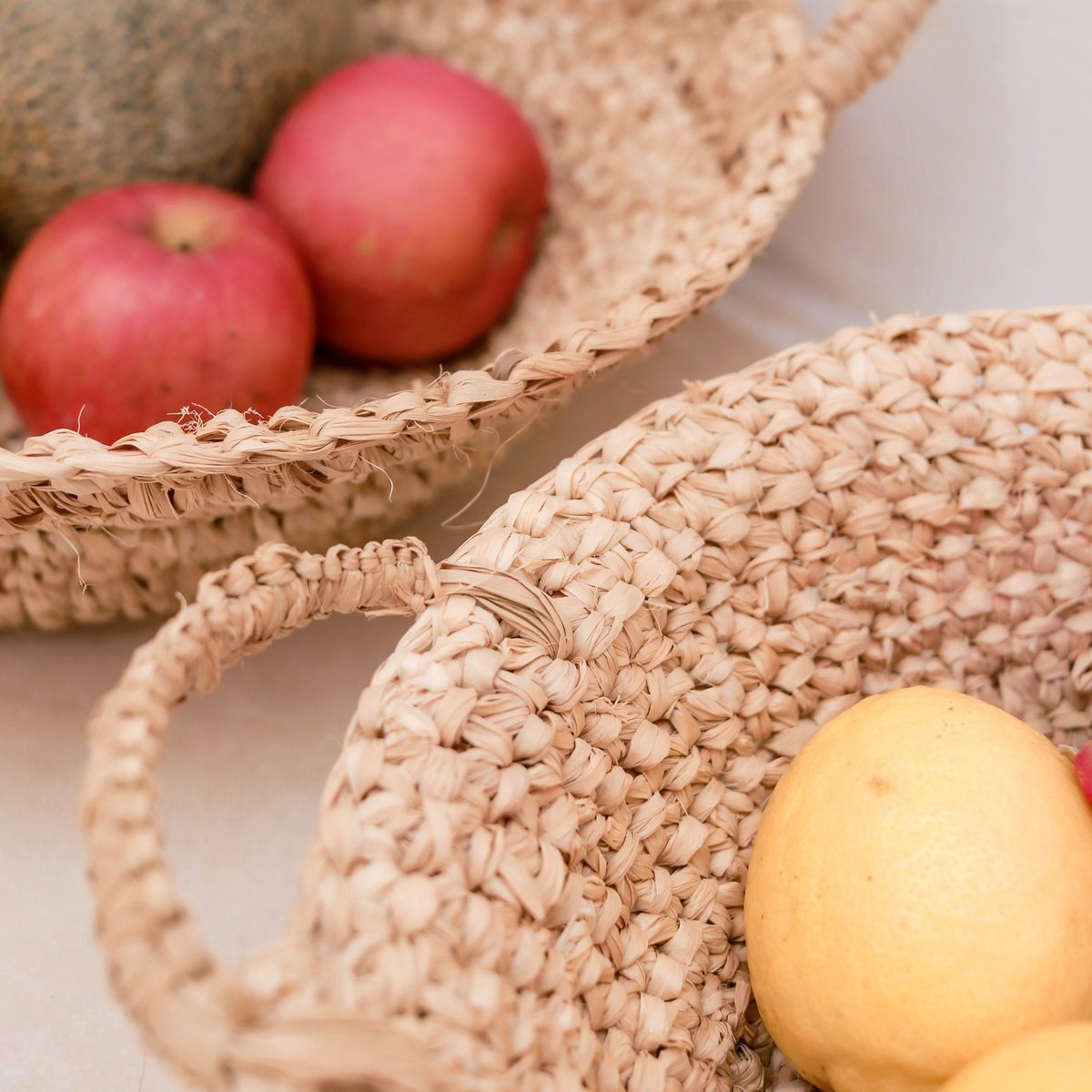 Twee fruitschalen van raffia met fruit erin ingezoomd