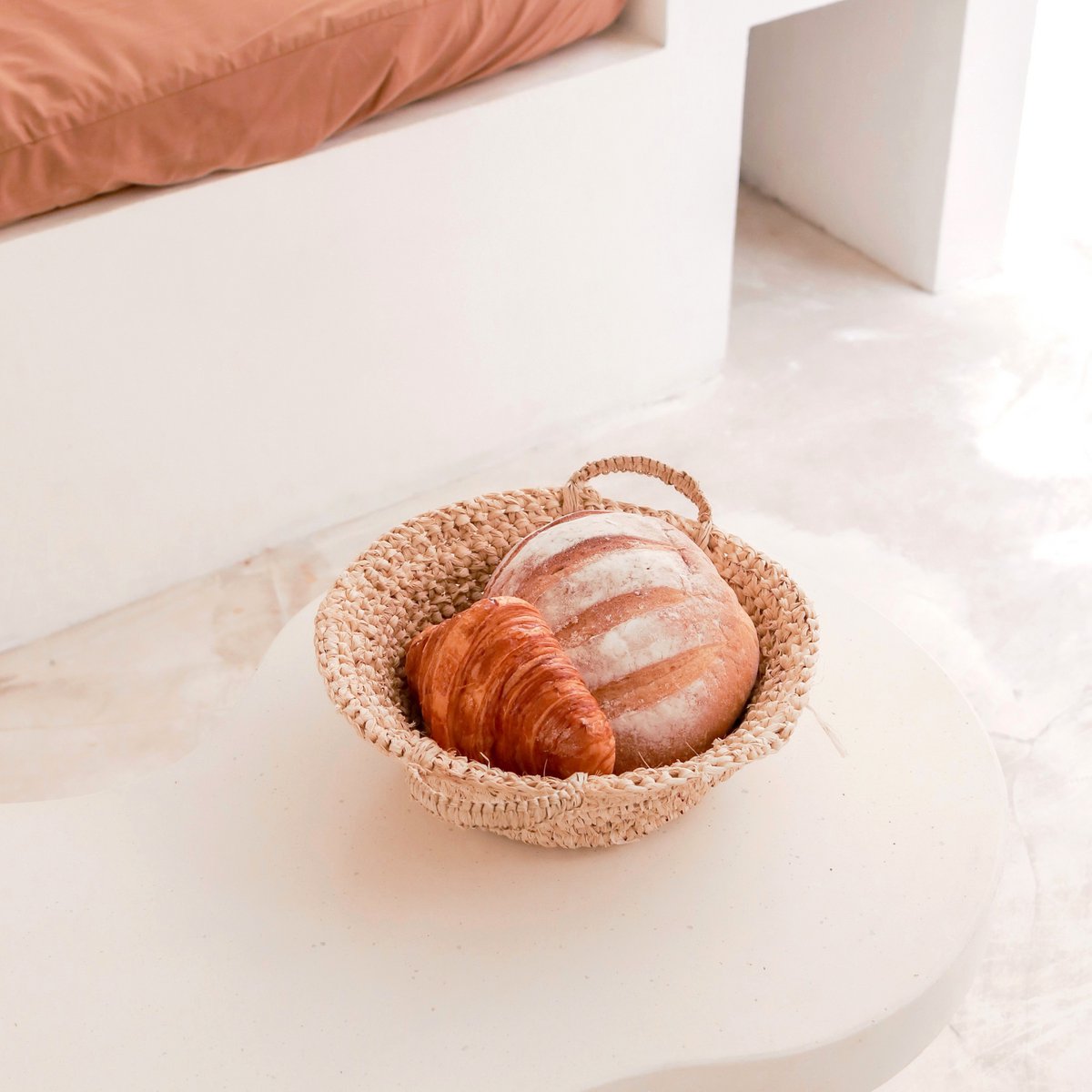 Fruitschaal van raffia staand op de grond met een brood erin