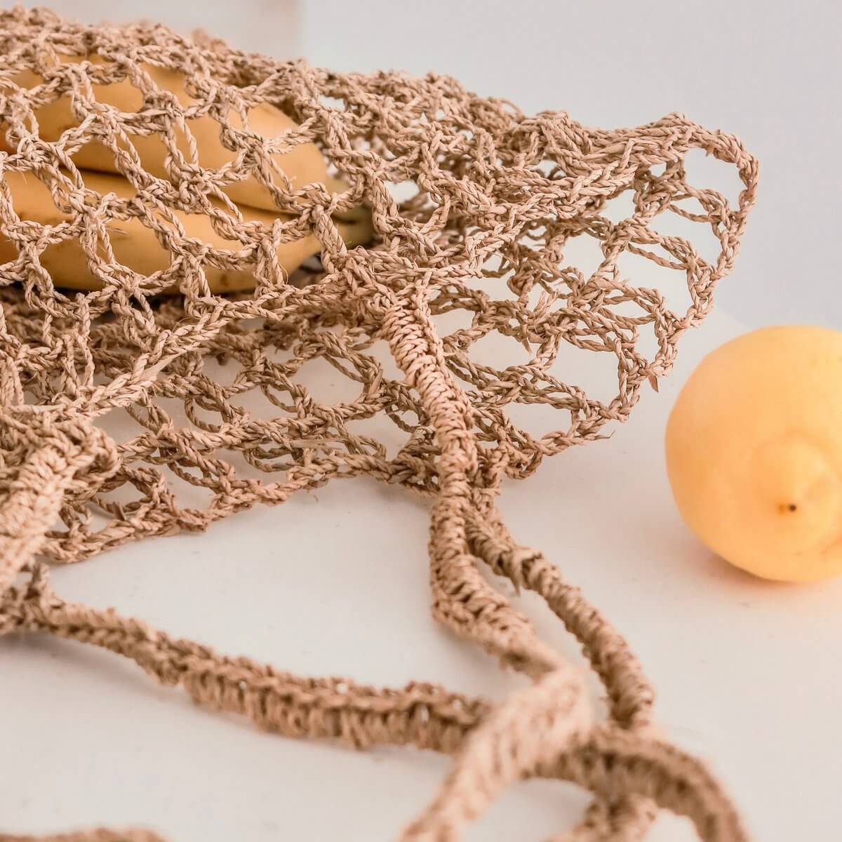 Geweven raffia touwtas met daarin een aantal stuks fruit ingezoomd