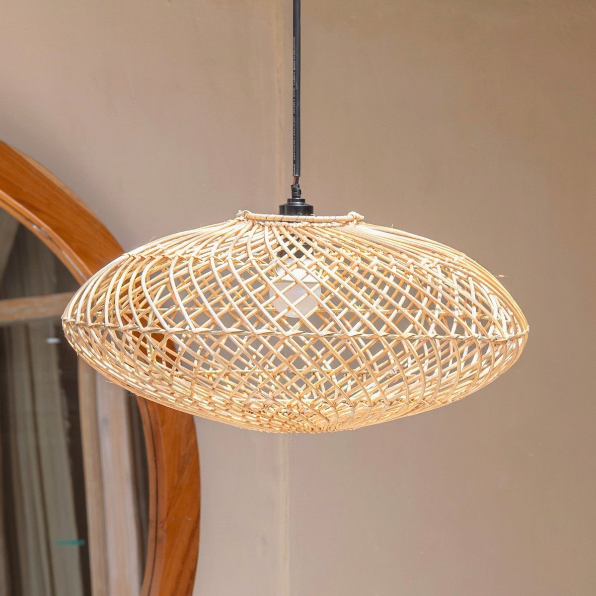 Hanglamp van rotan met een spiegel en muur erachter