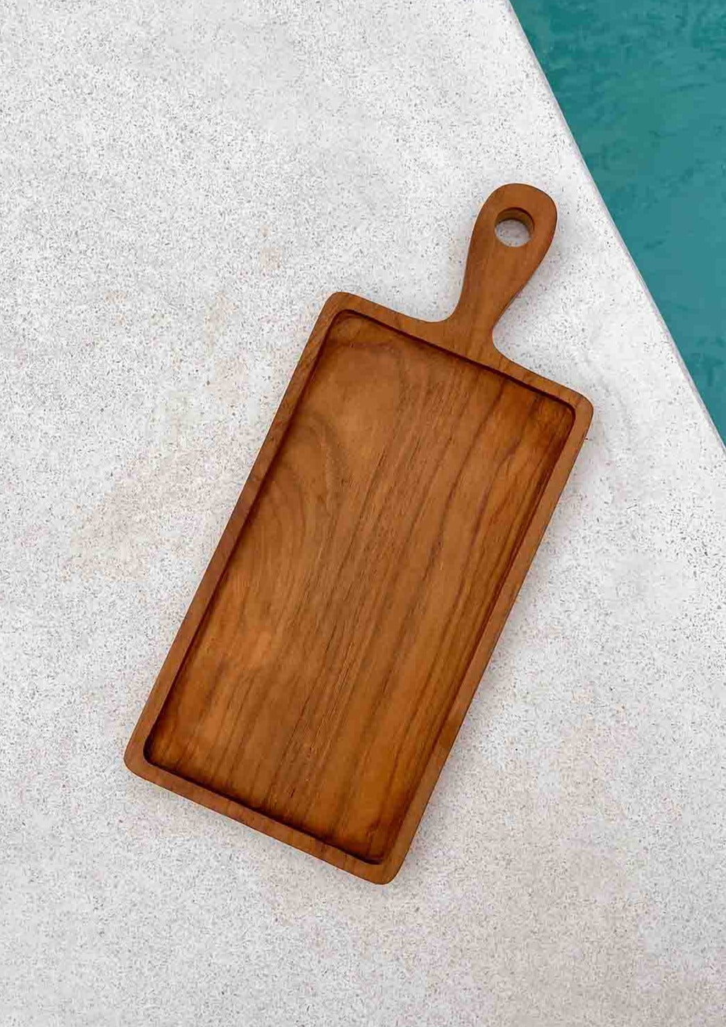 Houten borrelplank op de grond naast een zwembad