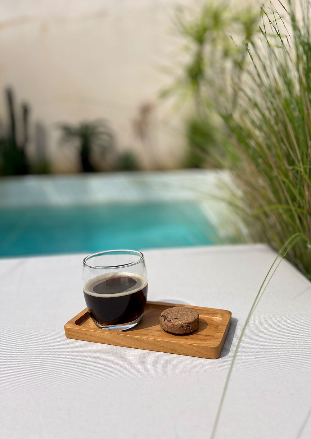 Houten plankje naast een zwembad met daarop een kopje koffie