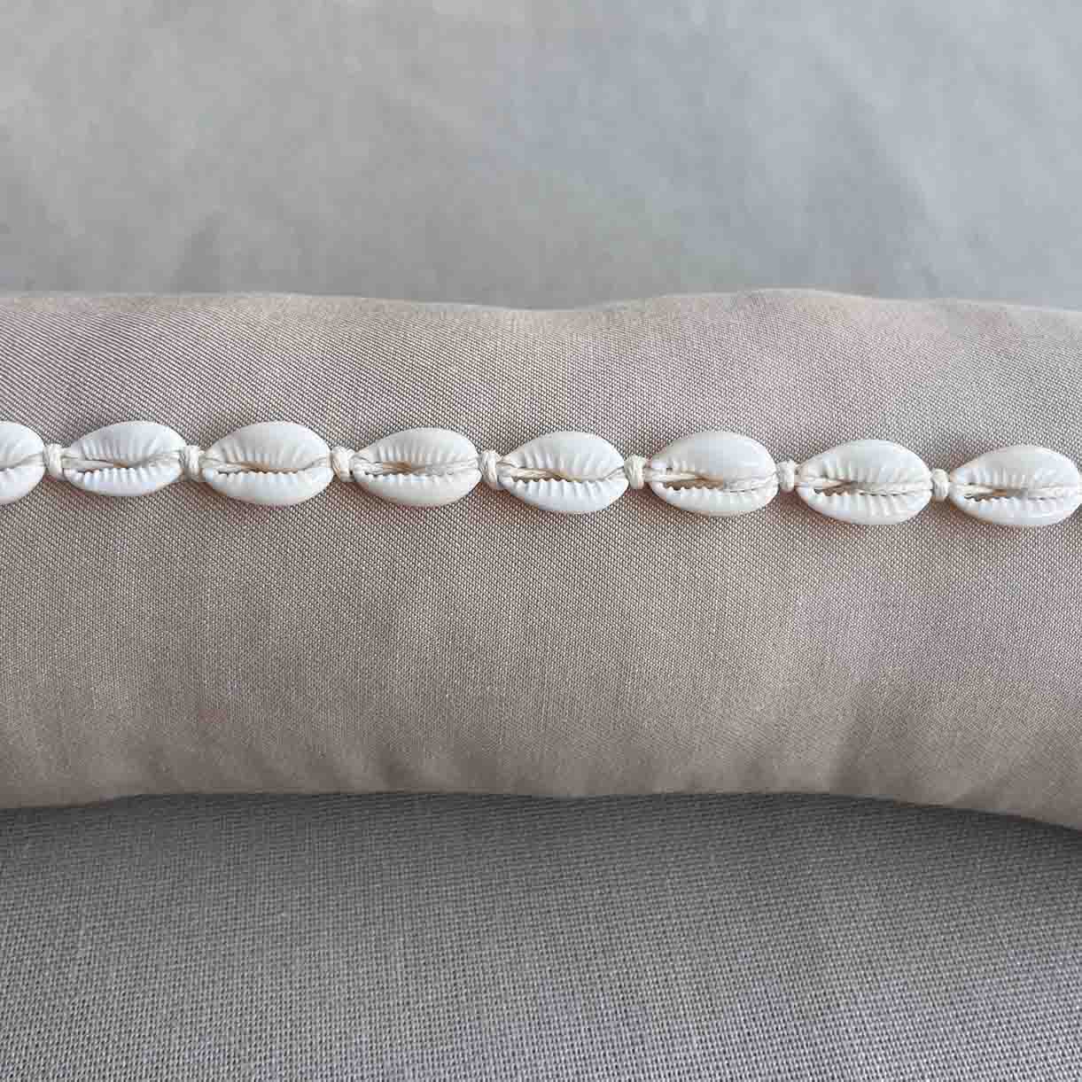 Ketting met kauri schelpjes op een kussentje