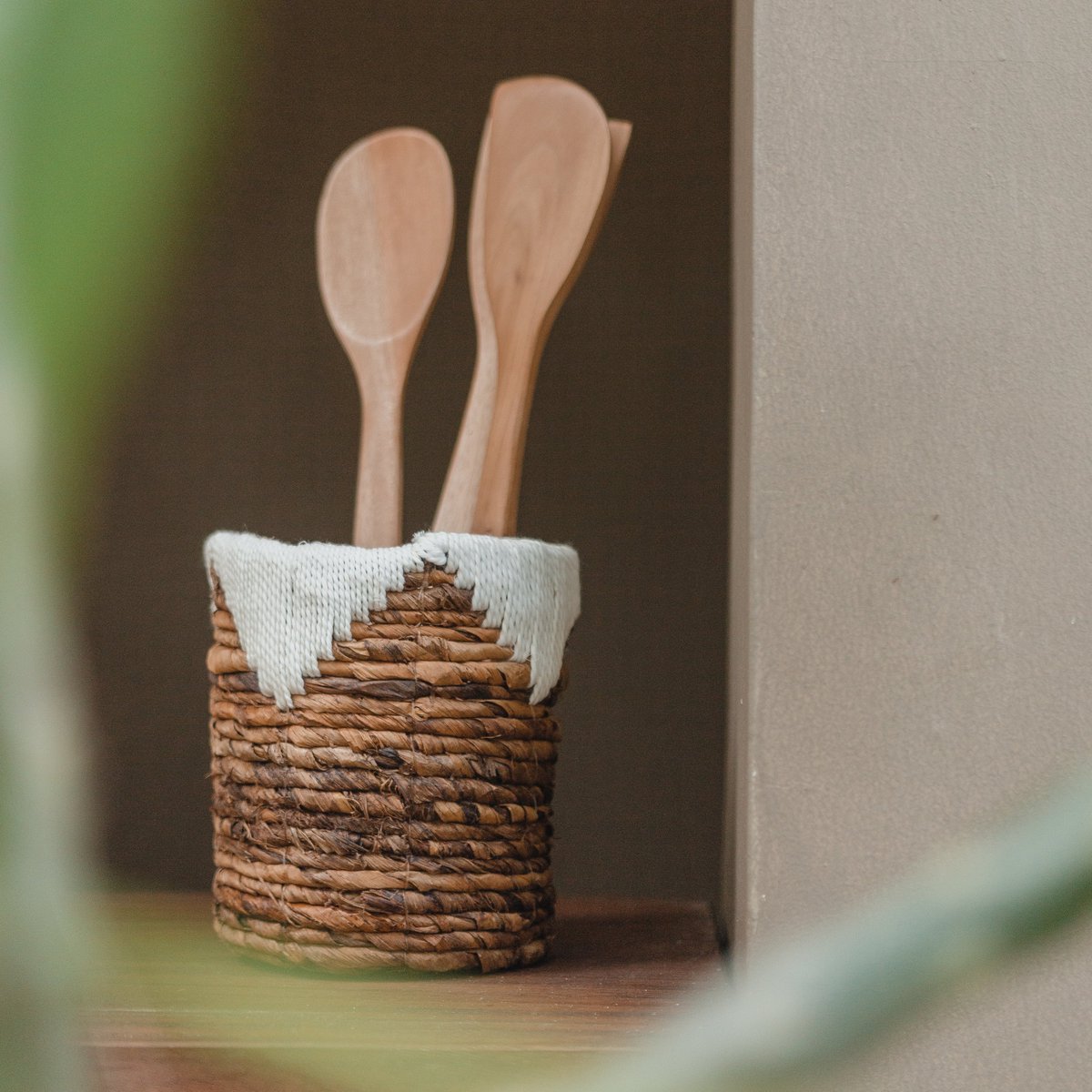 Kleine opbergmand van bananenvezel een katoen met houten lepels en spatels erin