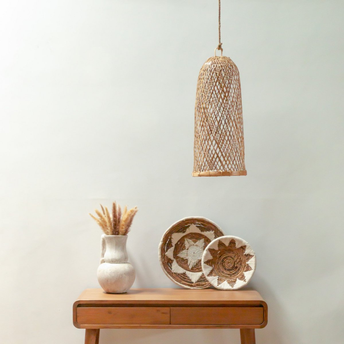Hanglamp van bamboe hangend aan het plafond voor een tafeltje met wandschalen erop