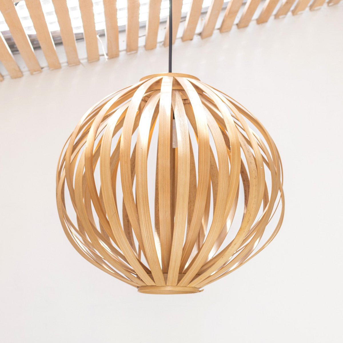 Hanglamp van bamboe van dichtbij gezien voor een witte muur