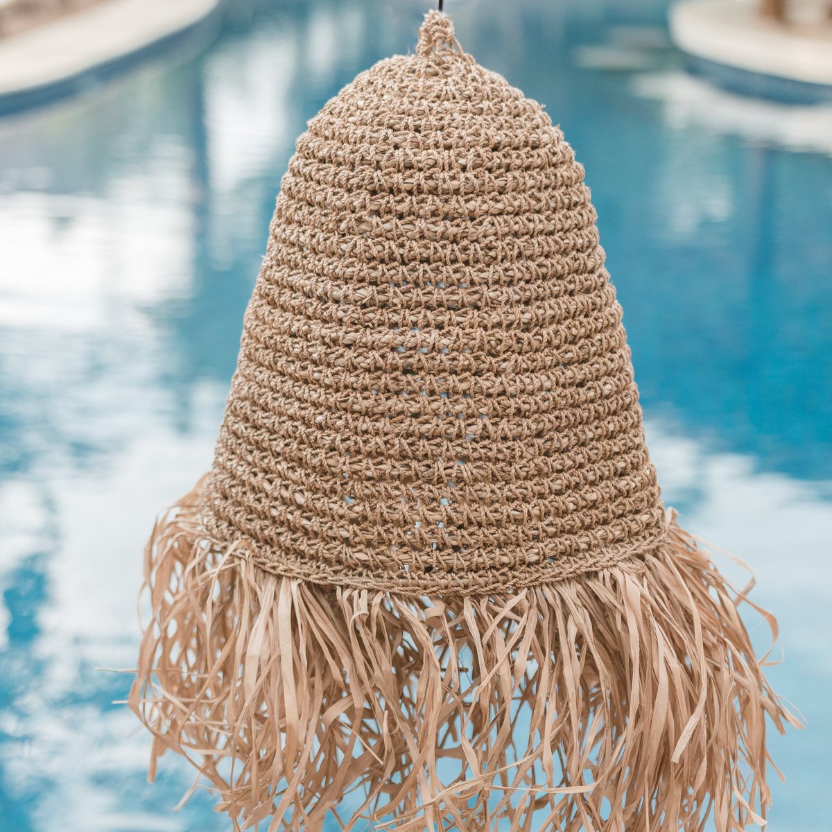 Lampenkap van raffia met een zwembad op de achtergrond