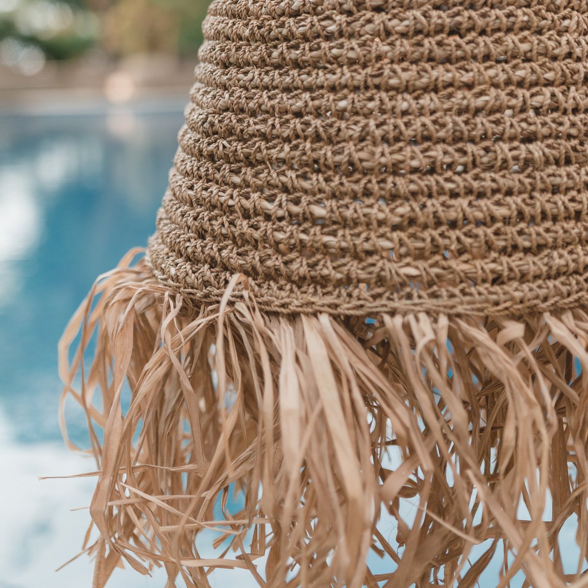 Lampenkap van raffia ingezoomd met zwembad op achtergrond