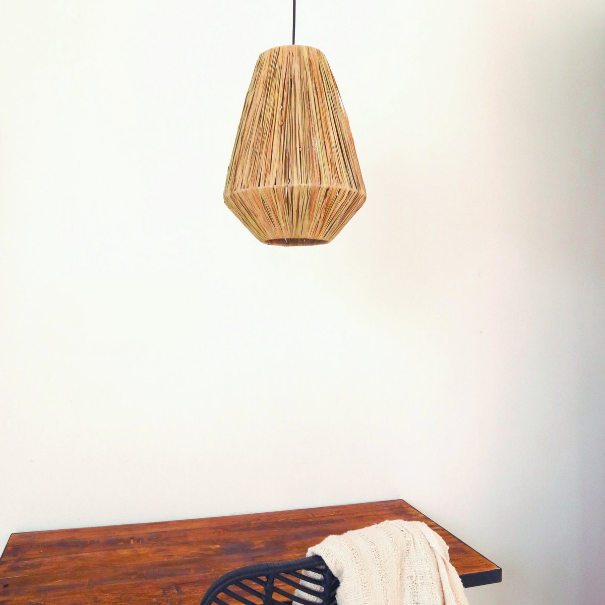 Lampenkap van raffia hangend voor een witte muur