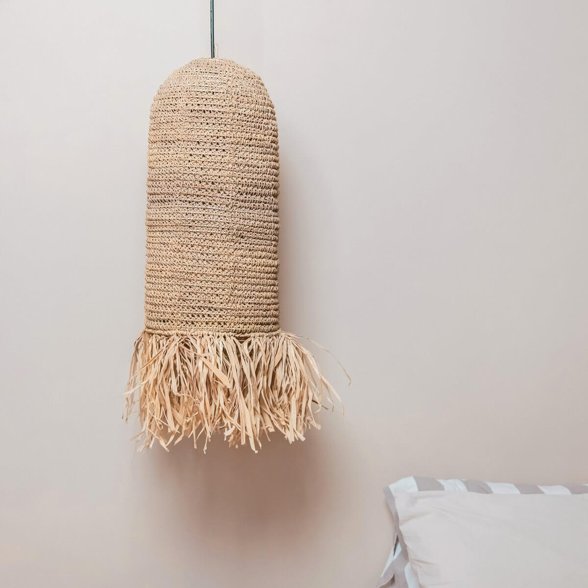 Lampenkap gemaakt van raffia hangend voor een muur