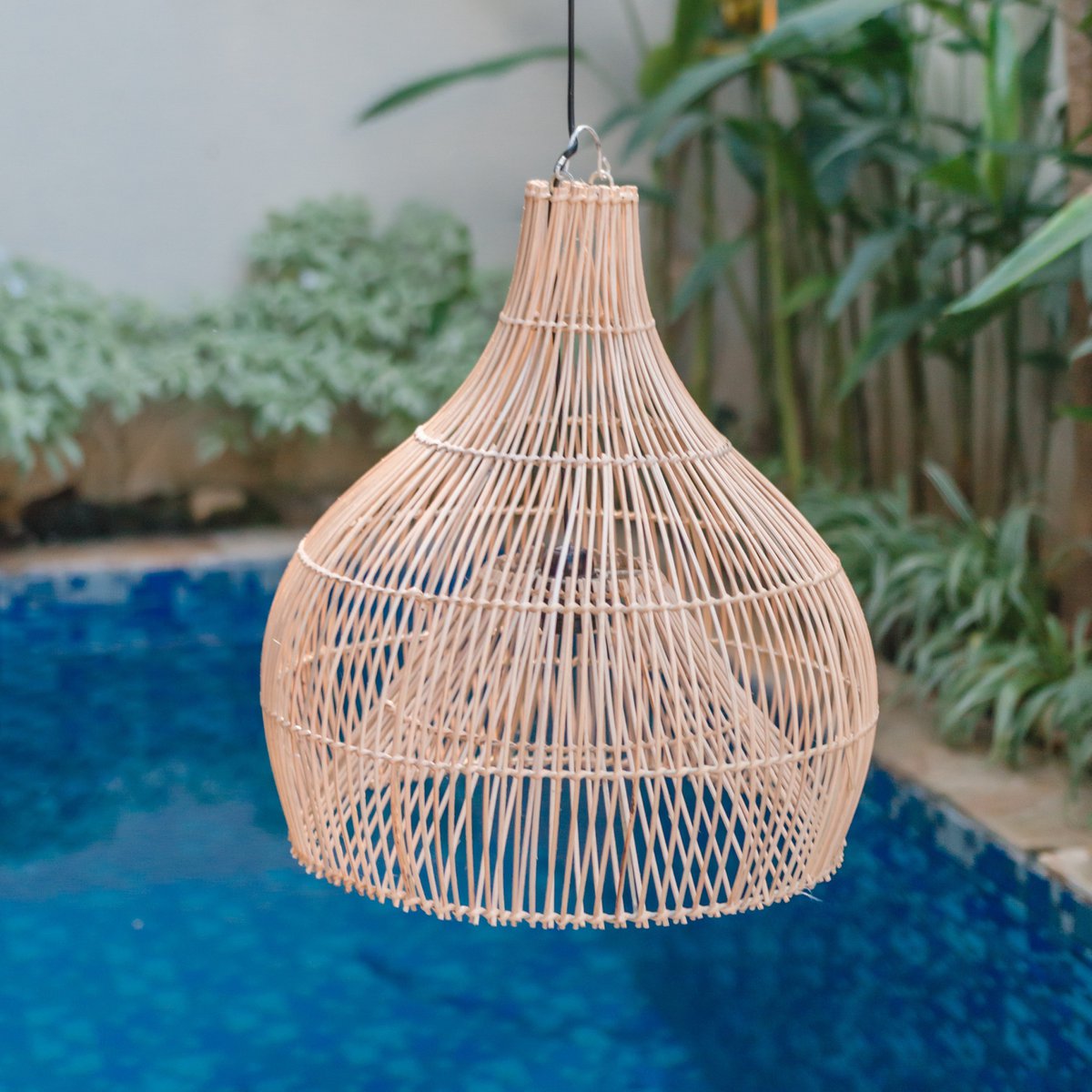 Hanglamp van rotan met een zwembad op de achtergrond