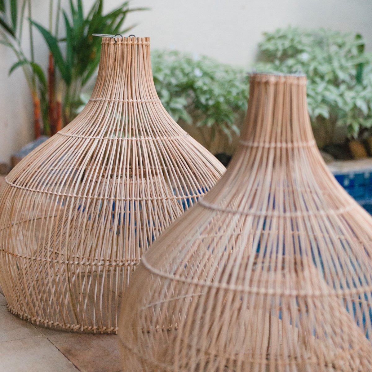 Twee lampenkappen van rotan naast een zwembad van dichtbij gezien