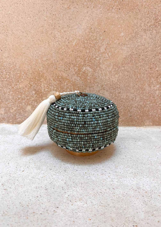 Rond offermandje staand op de grond voor een muur