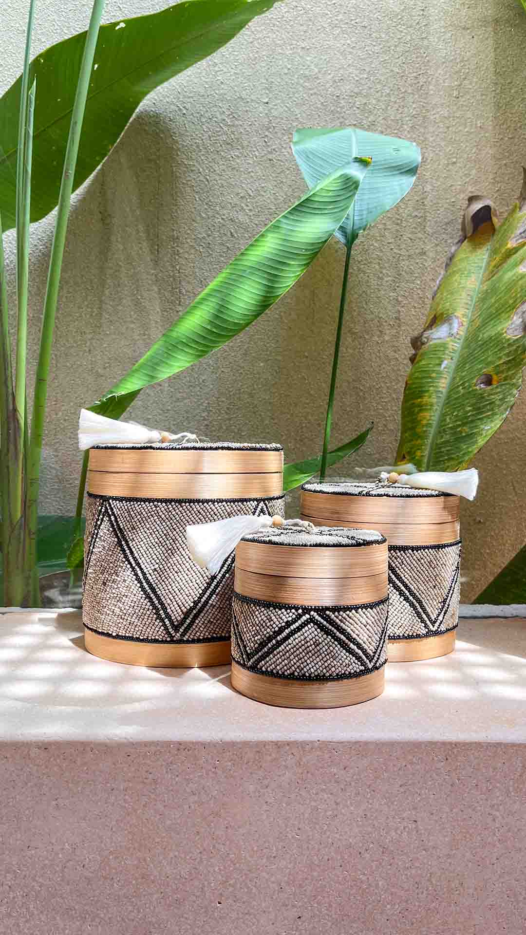 Set van drie offermandjes voor een raam met planten erachter