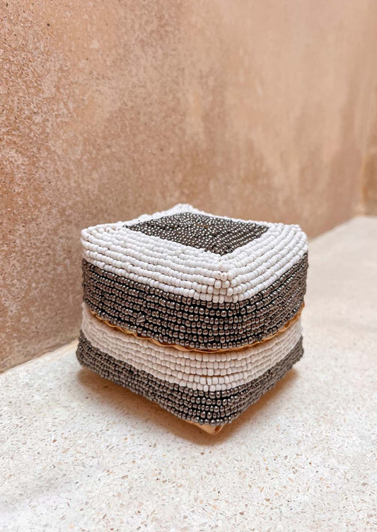 Offermandje staand op de grond voor een muur