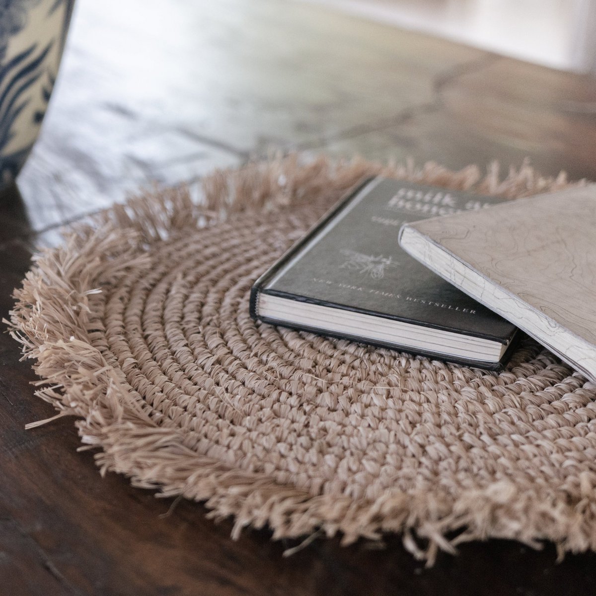 Placemat van raffia op houten tafel met twee boeken erop
