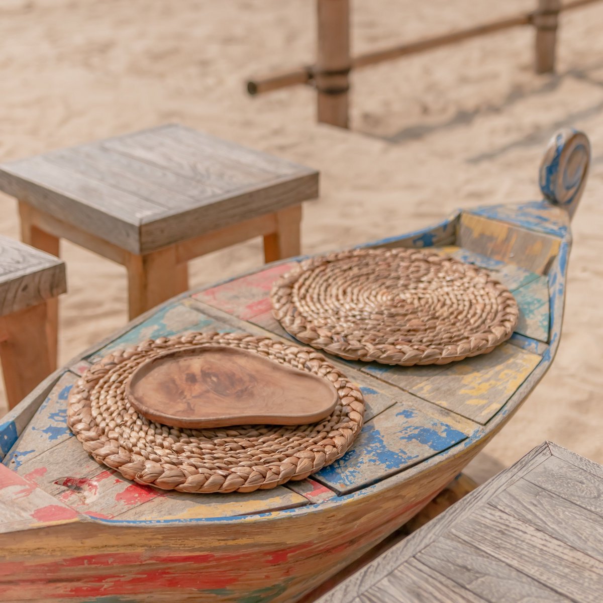 Twee ronde placemats van waterhyacint op een houten tafel op het strand