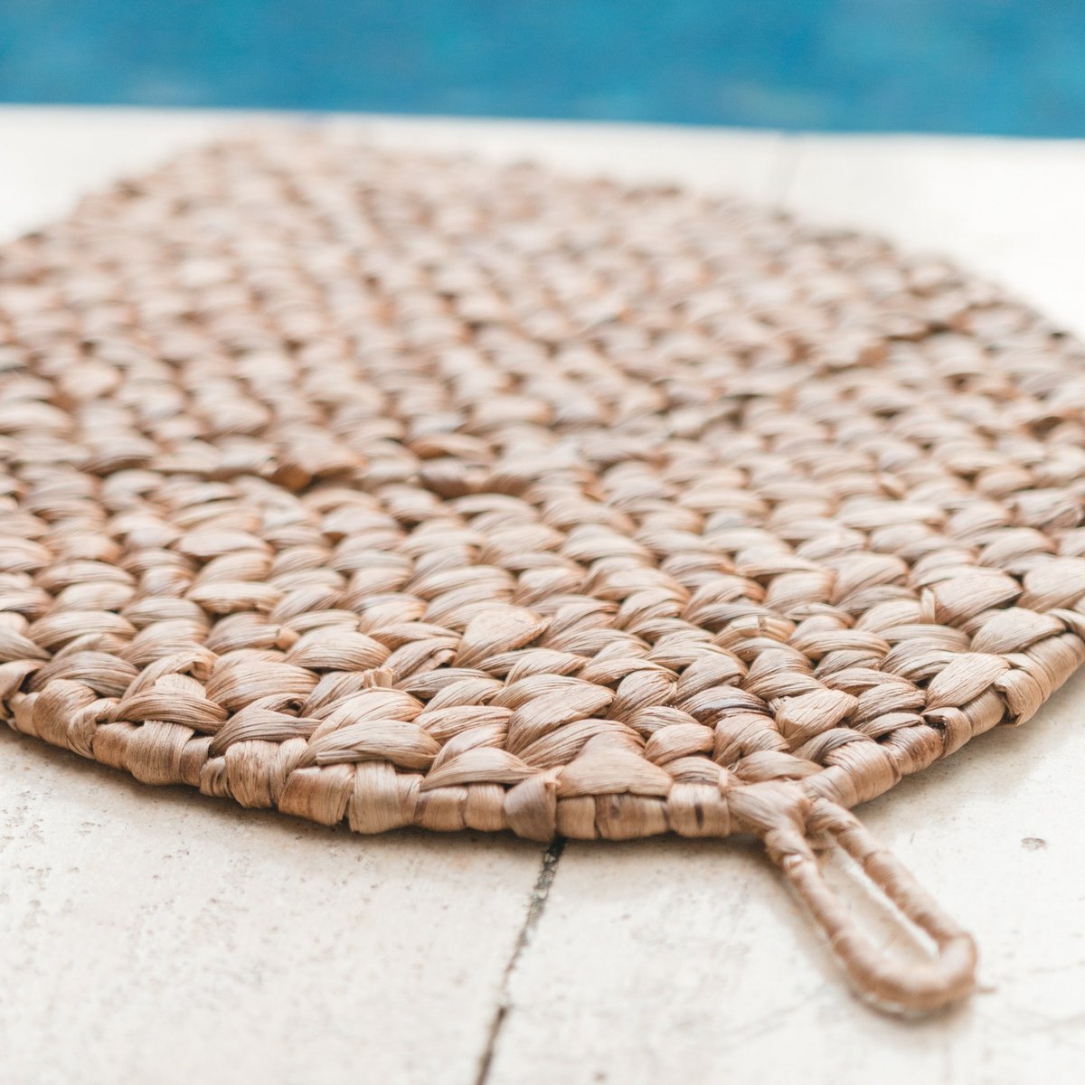 Placemat van waterhyacint op de grond naast een zwembad