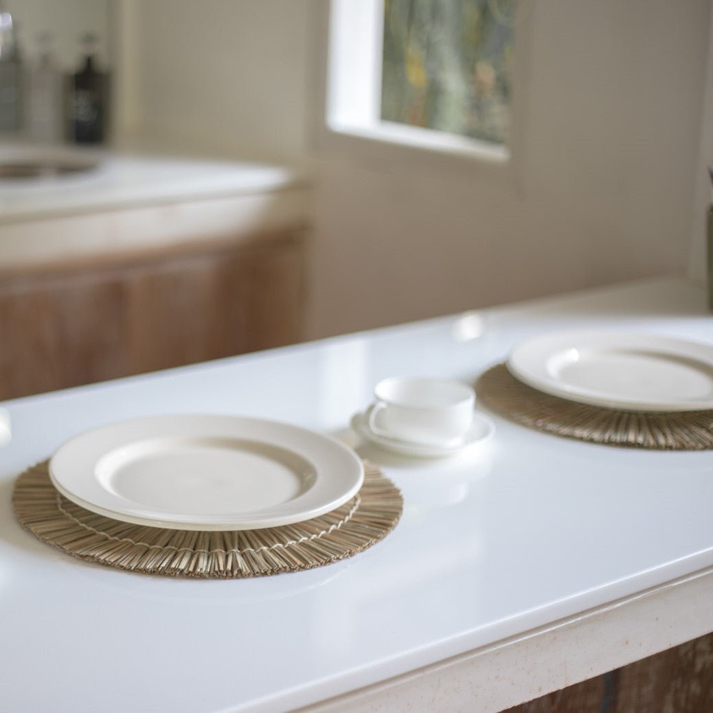Twee placemats van zeegras met borden erop op een tafel