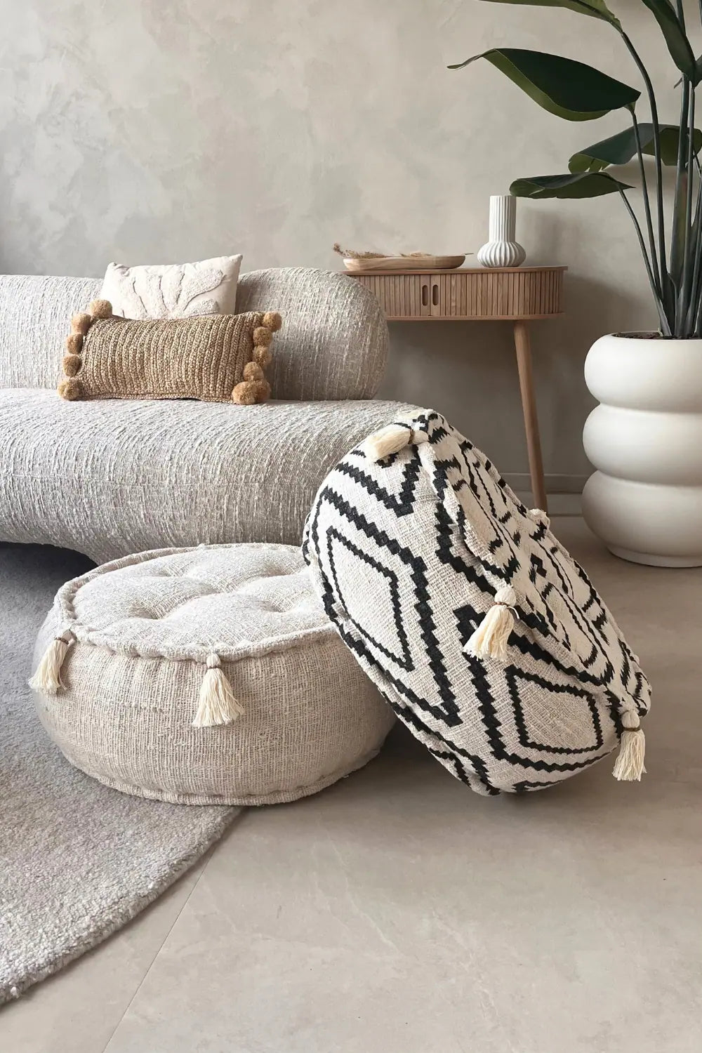 Twee ronde poefs van katoen waarvan een creme en een zwart wit op elkaar gestapeld