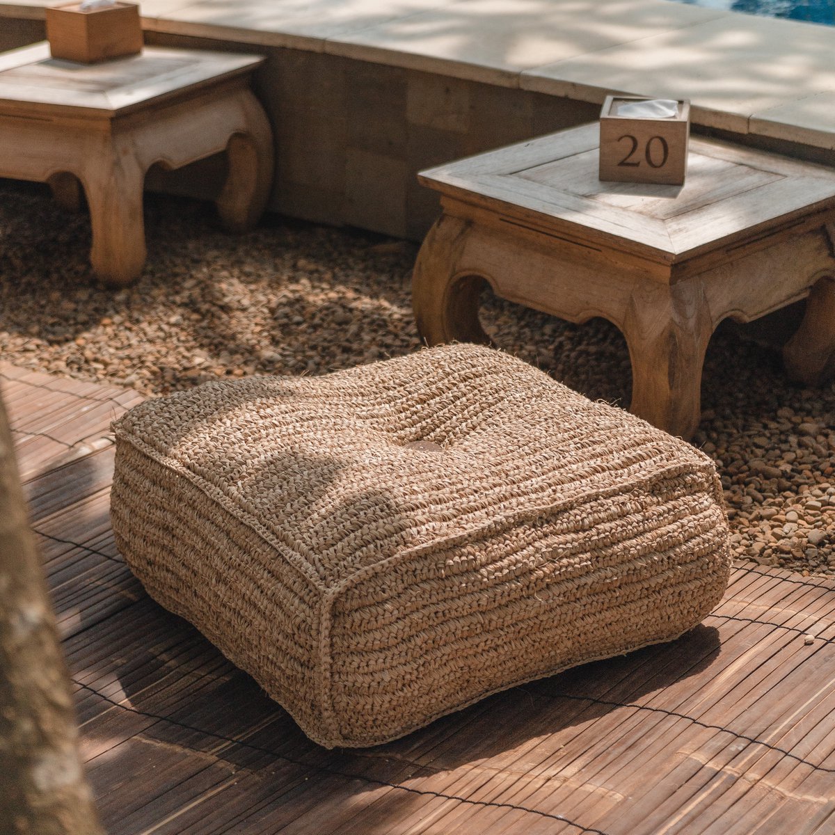 Vierkante grote poef van raffia op een terras