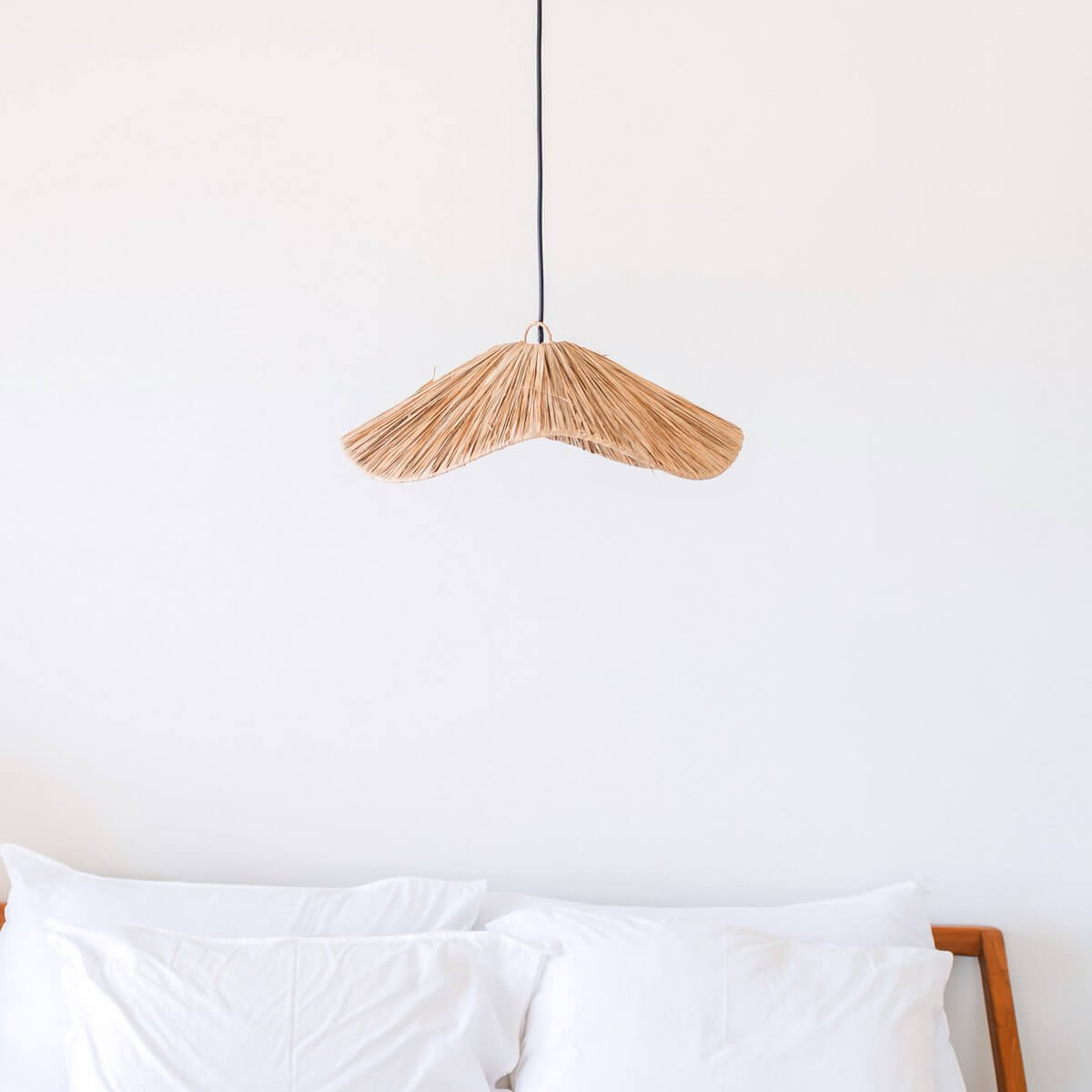 Raffia lampenkap hangend boven een bed