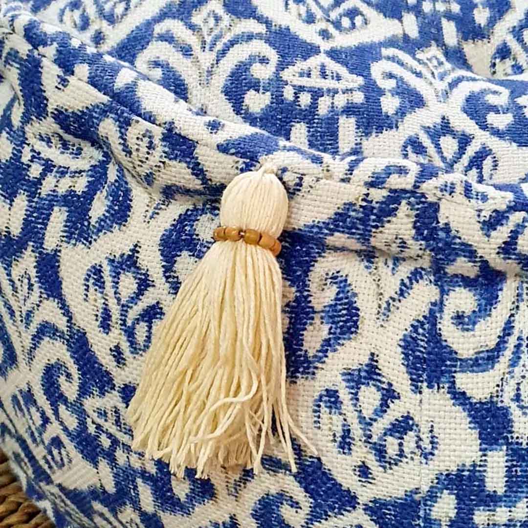 Het blauw witte katoen gezien van de zijkant van een kleine ronde poef, met een wit kwastje eraan