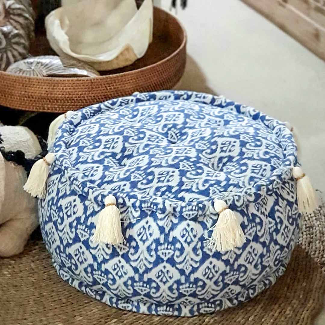Ronde kleine blauw witte poef schuin van boven gezien, liggend op een tapijt