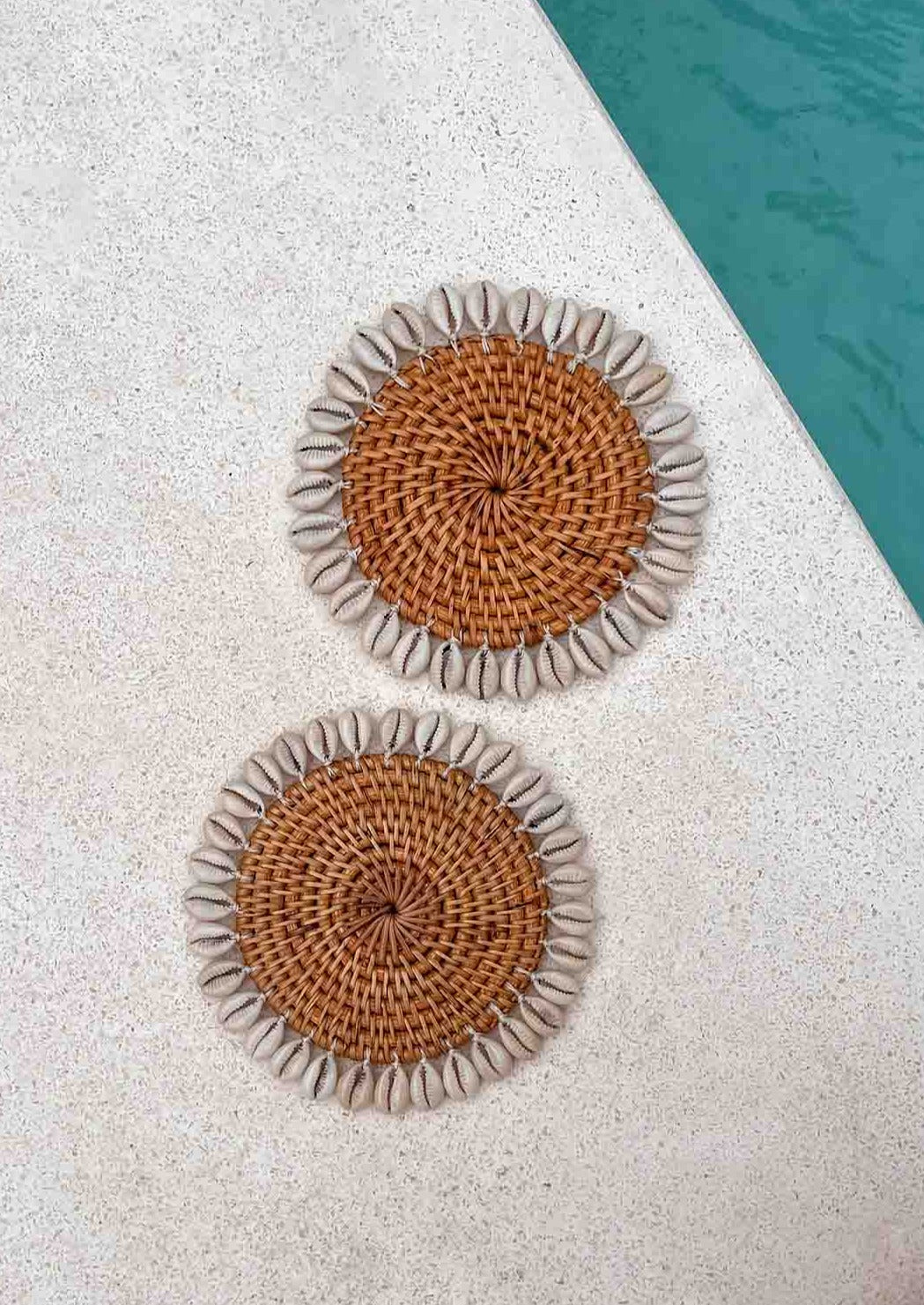 Twee schelpen onderzetters naast een zwembad