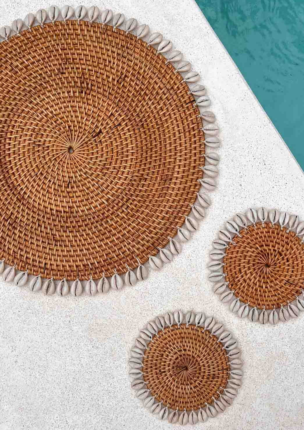 Twee schelpen onderzetters en een placemat naast een zwembad