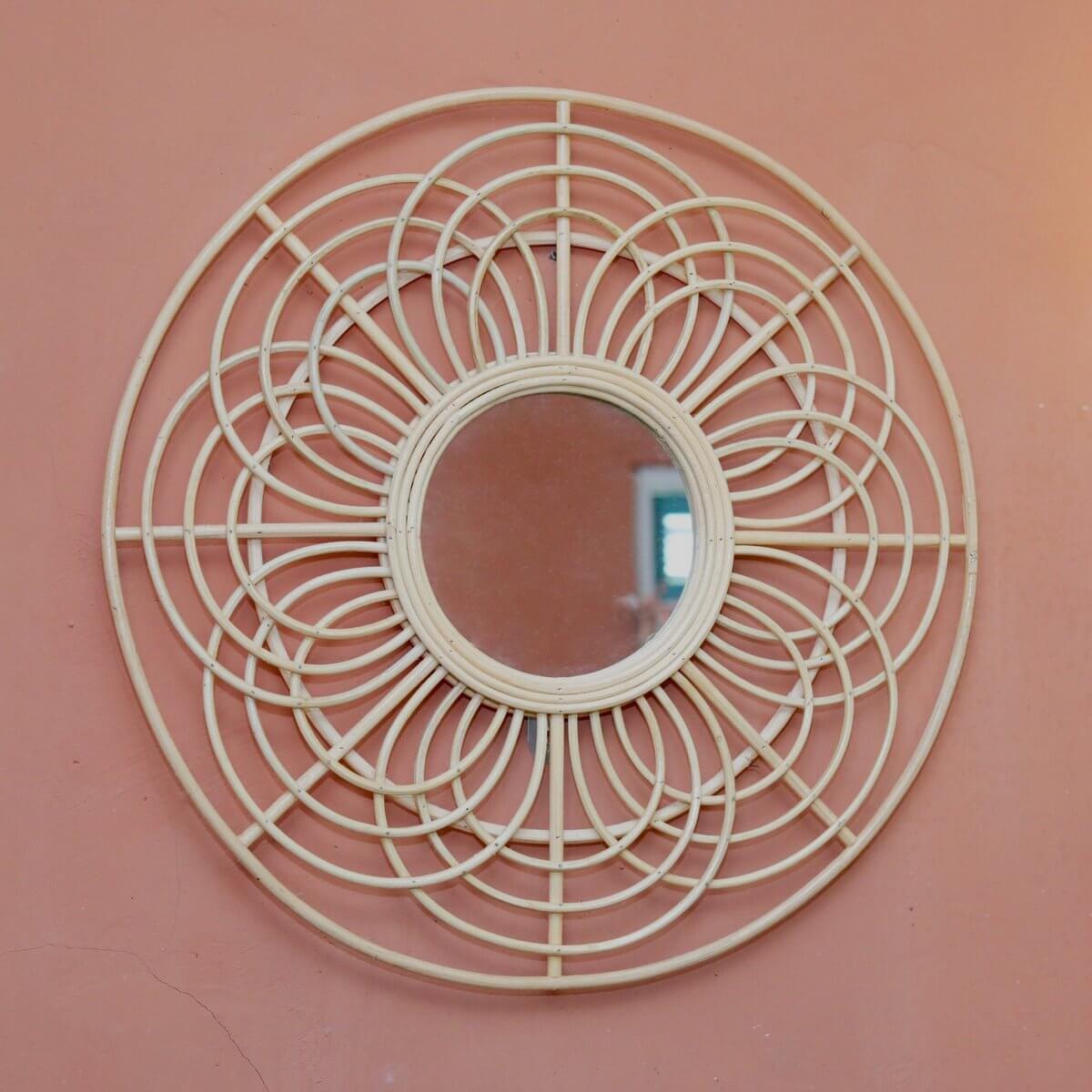 Ronde rotan spiegel hangend aan een rode muur
