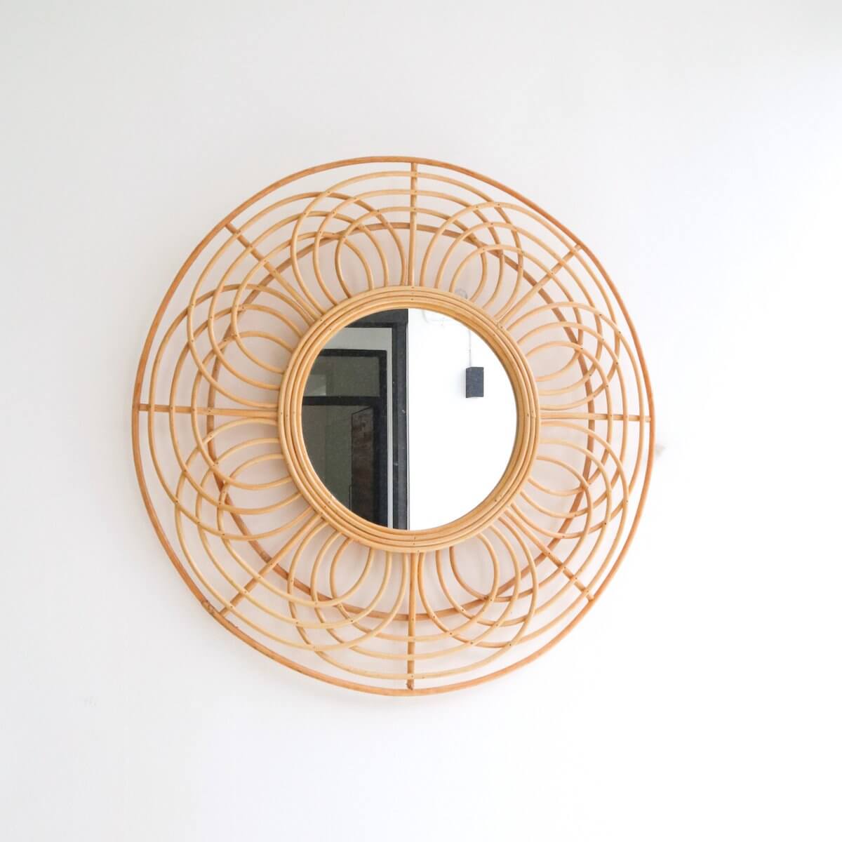 Ronde rotan spiegel hangend aan een witte muur