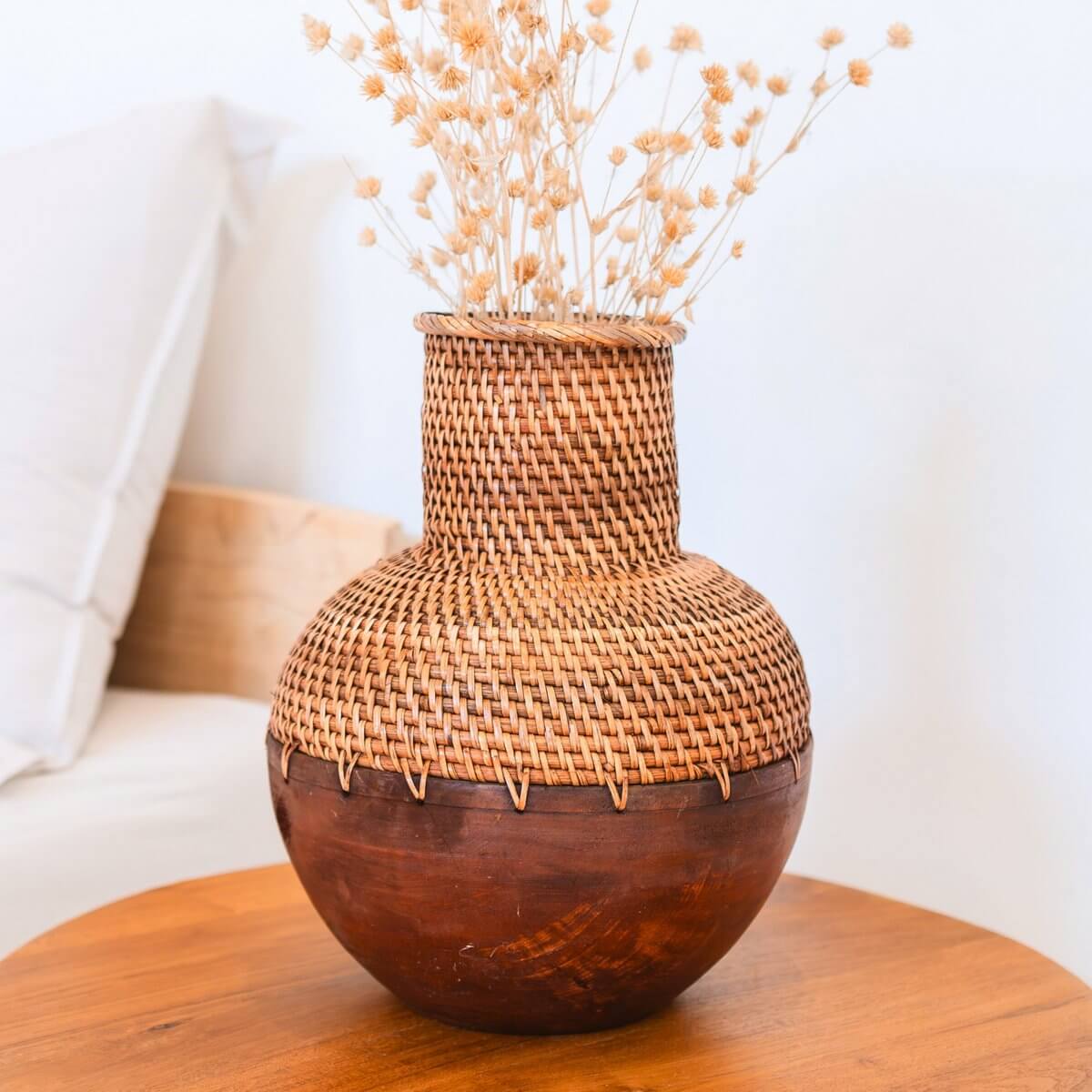 Vaas van rotan en hout met bloemen erin van dichtbij gezien