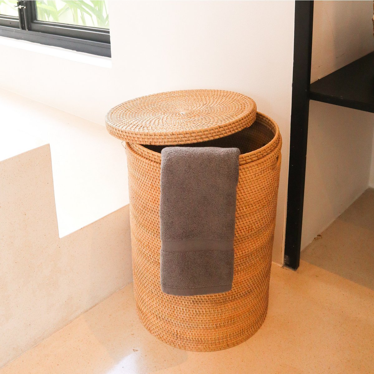 Rotan wasmand met de deksel half erop en een handdoek erin