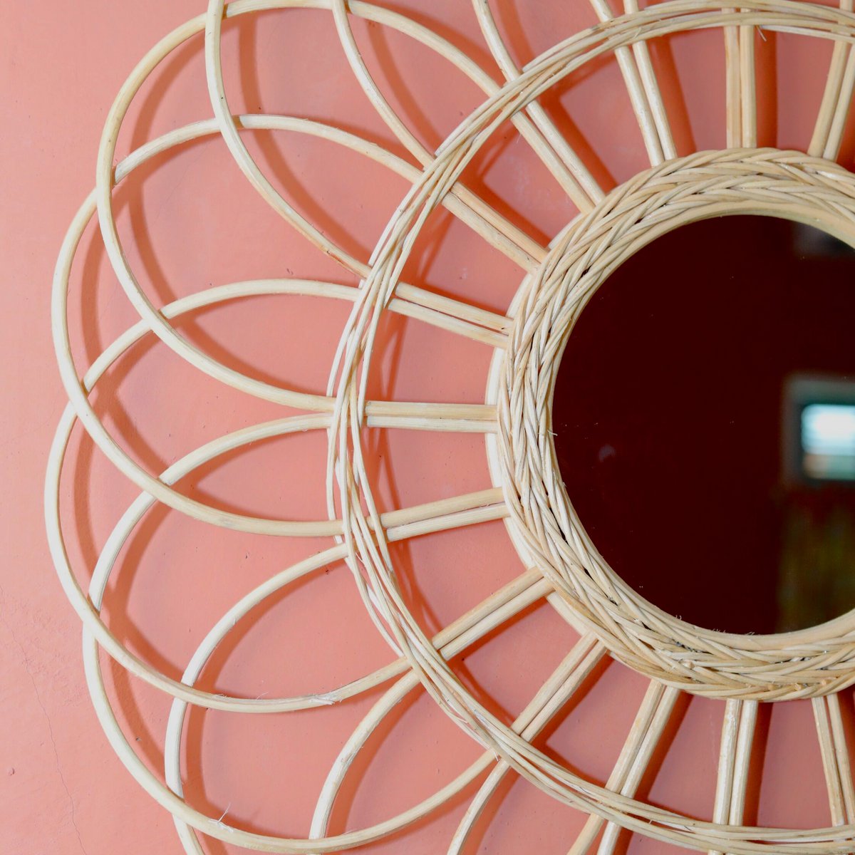 Wandspiegel van rotan op een roze muur ingezoomd
