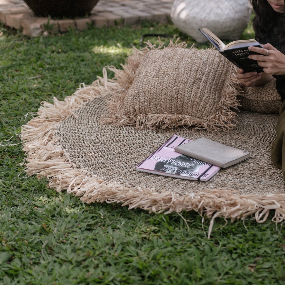Vloerkleed van zeegras met een kussen en boeken erop