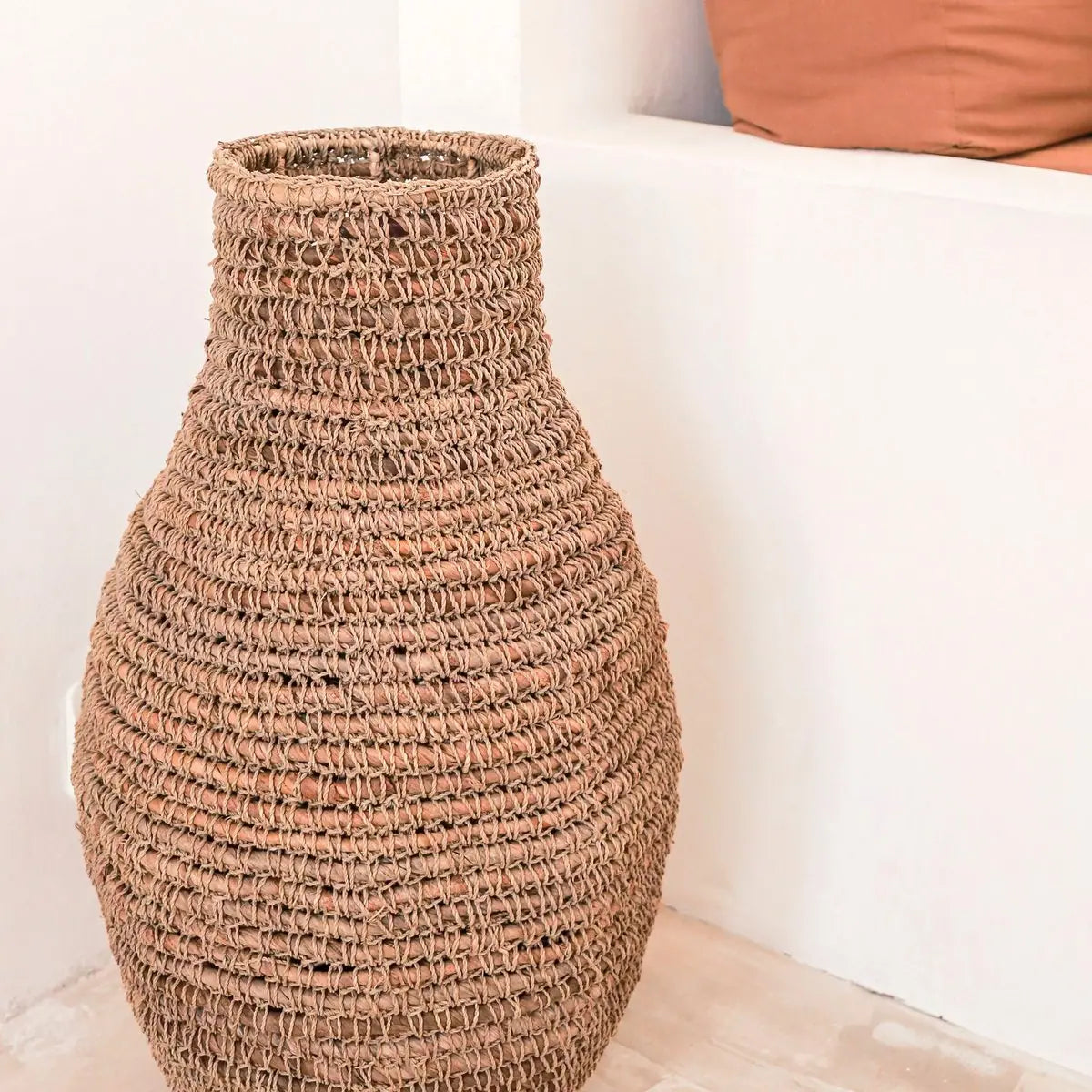 Vaas van bananenvezel en raffia voor een witte muur